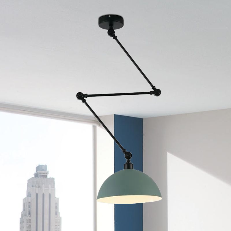 Green dome pendant on a black jointed arm by a large window and blue wall