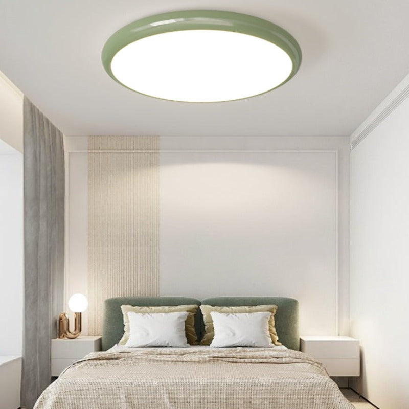 Green Ozawa round ceiling light in a bedroom with green cushions.
