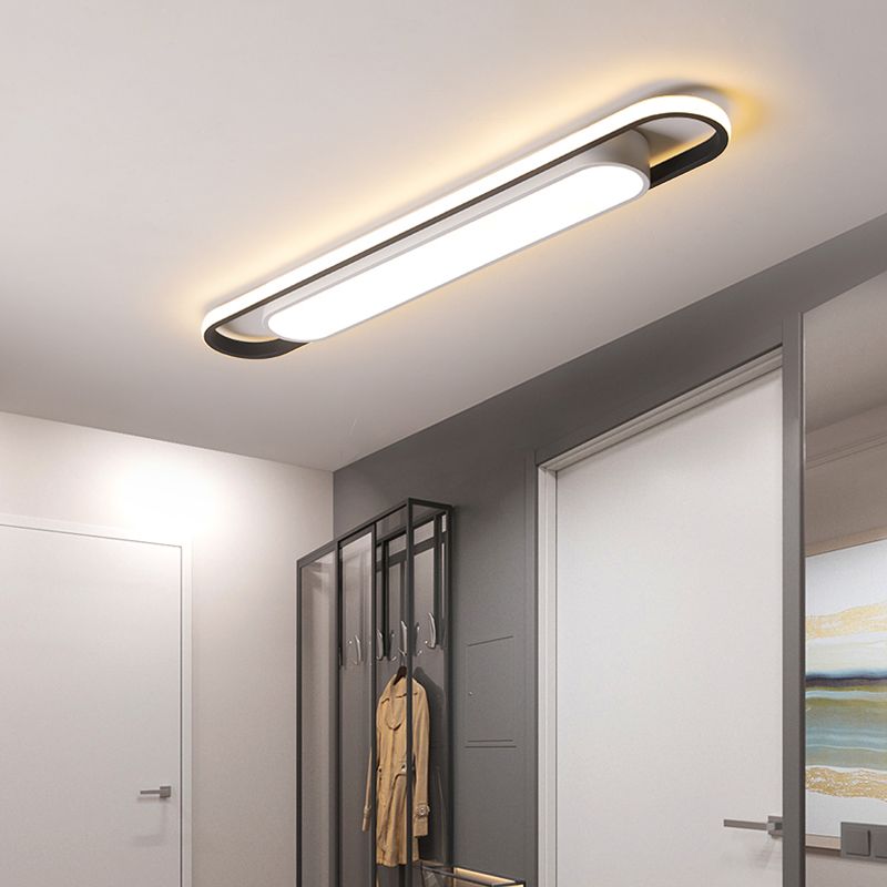 Lit rounded linear ceiling fixture above an entry coat stand and door frames