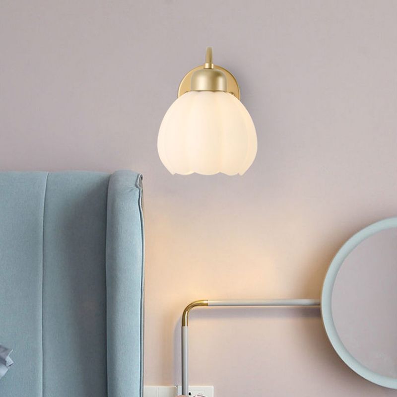 Front view of a scalloped glass wall light beside a blue headboard and a round mirror