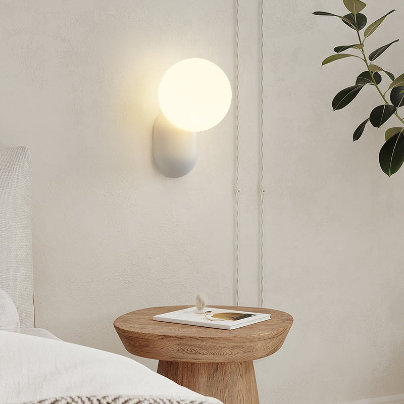 White globe and resin Hailie wall lamp above a small round table