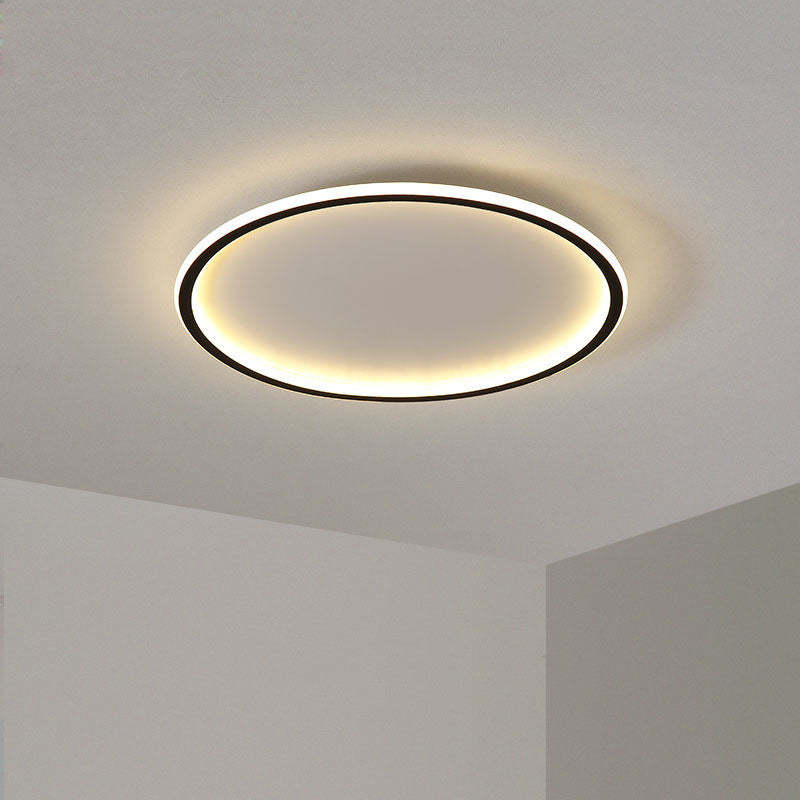 Black-edged LED ring with a warm-looking illuminated rim at the corner of a pale ceiling