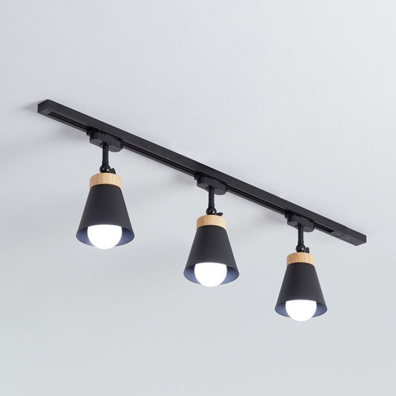 Black Haney ceiling rail with three cone shades, short jointed stems, light wood-tone collars and visible bulbs on gray background