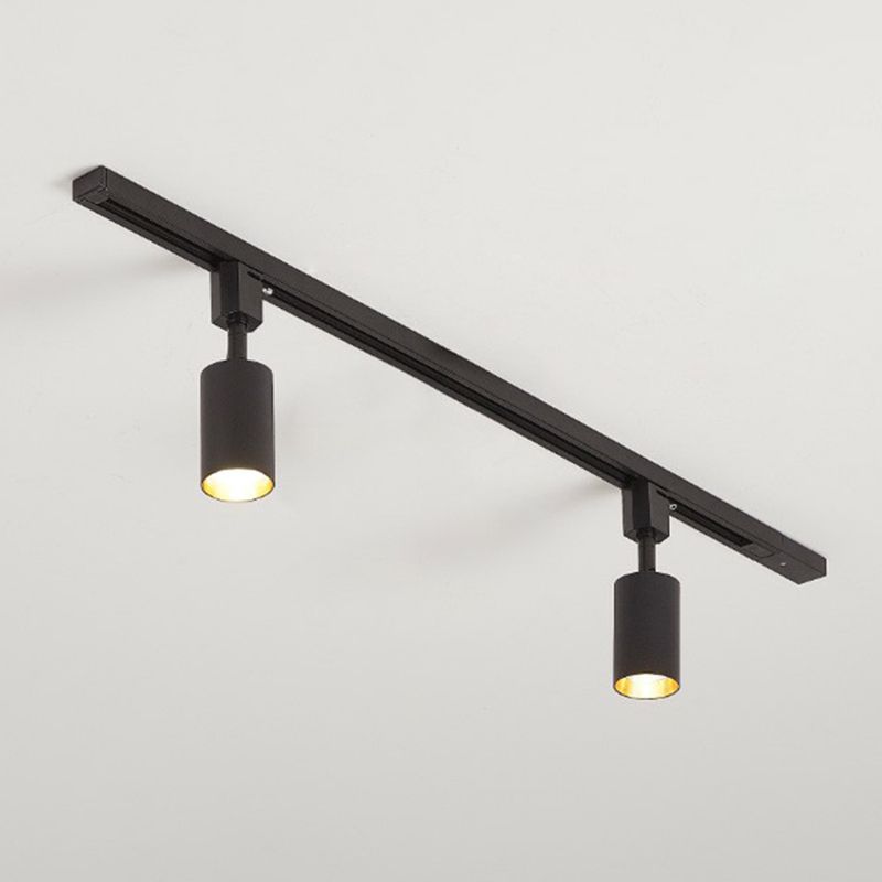 Small black two-head ceiling spotlight with short cylinders and lit gold-tone interiors