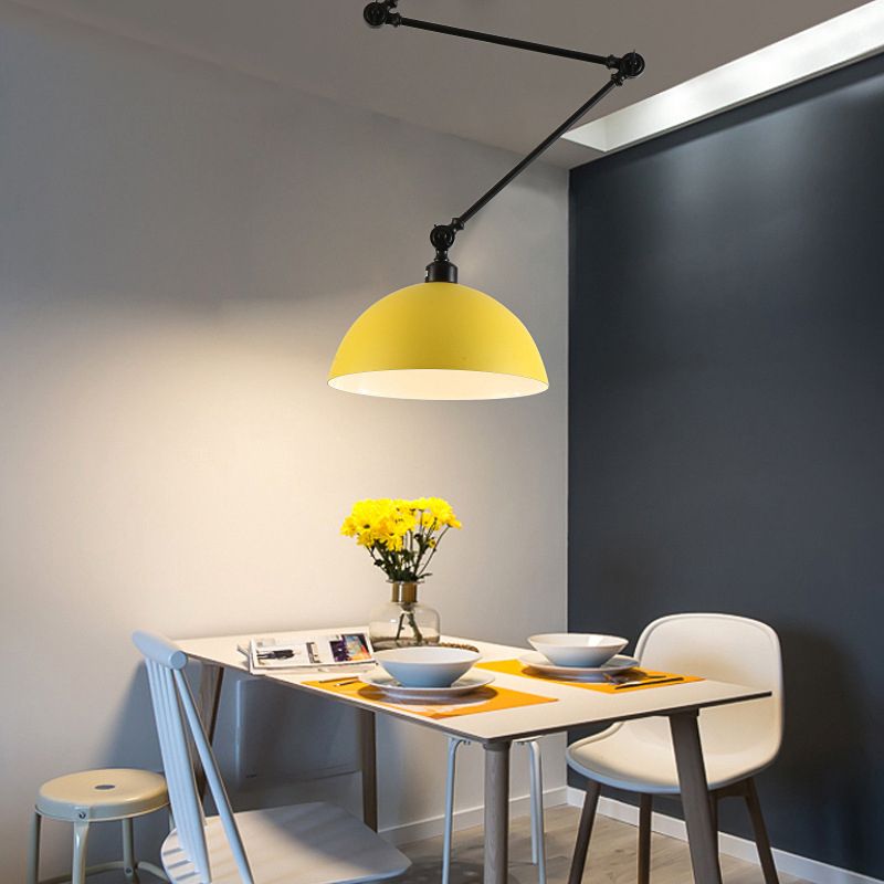 Yellow dome pendant with a black jointed arm above a small dining table and yellow flowers