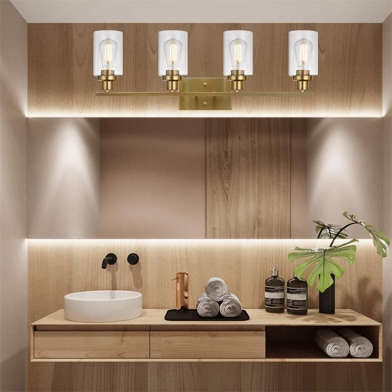 Gold Alessio four-light bar with upward clear glass cylinders above a wooden vanity