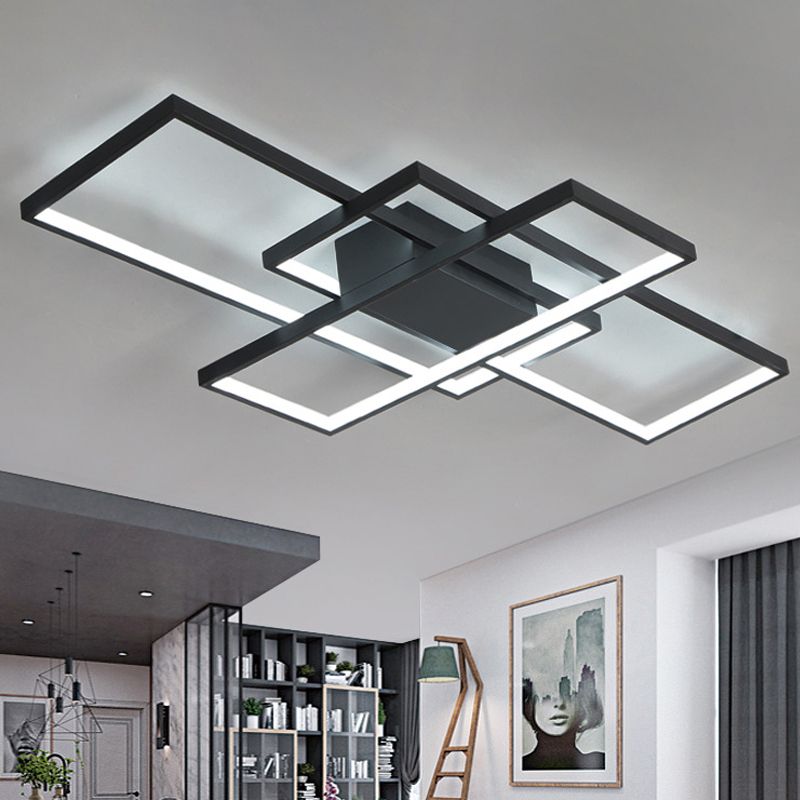 Black rectangular-frame ceiling light above seating near open bookshelves and a green lampshade
