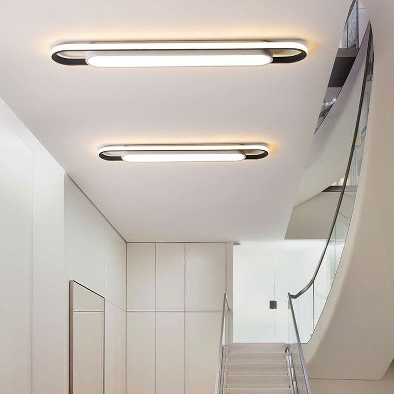 Two lit linear ceiling fixtures above an indoor stair landing
