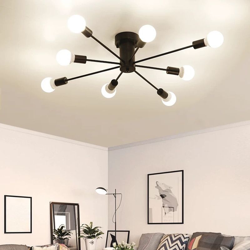 Black eight-light ceiling fixture above a grey sofa, patterned cushions, framed art and standing mirror