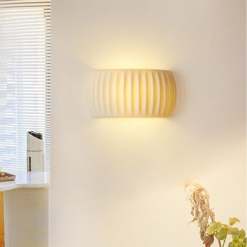 White ribbed wall light near a window casting light above and below