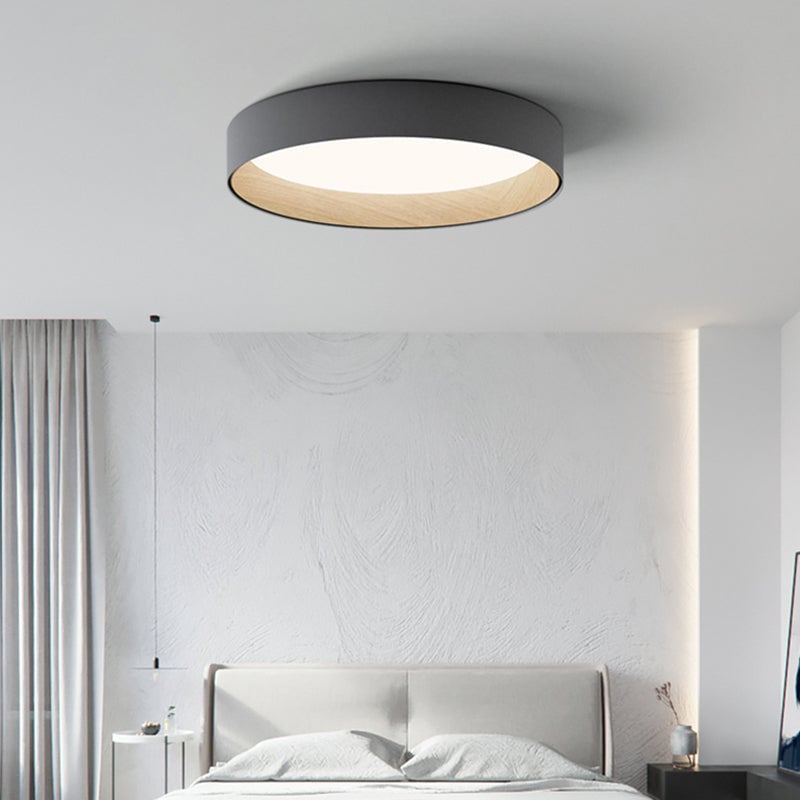 Gray Quinn round ceiling light above upholstered bed, with light wood-tone inner rim and glowing circular diffuser