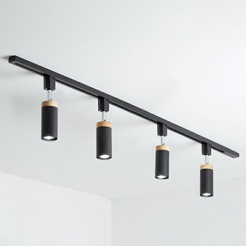 Black four-head rail fixture with cylindrical spotlights facing down and short silver-tone stems