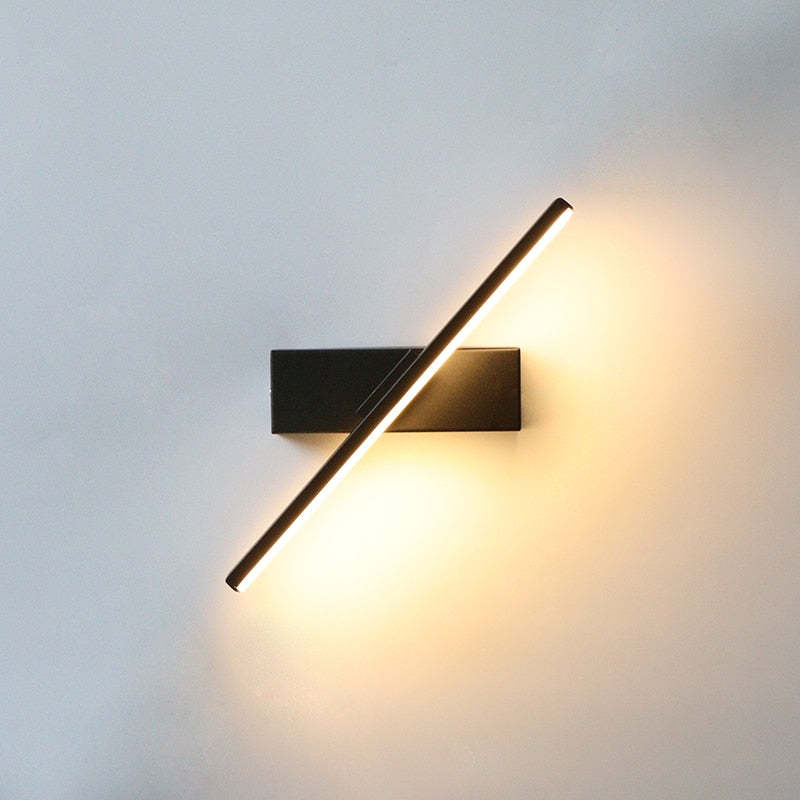 Close-up of a tilted black wall-light bar and illuminated diffuser