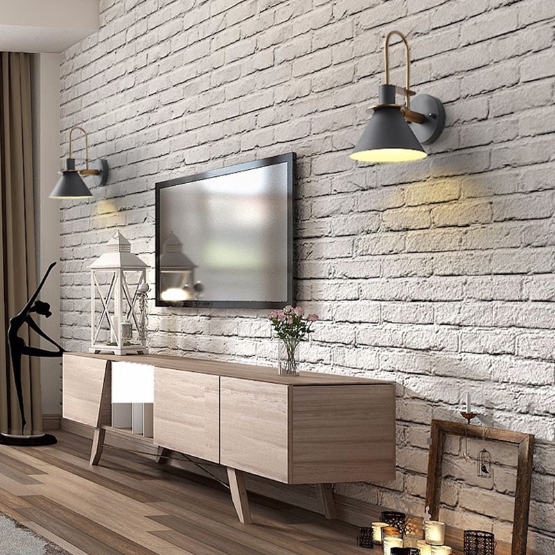 Two grey wall sconces flanking a television on a white brick wall above a wooden cabinet