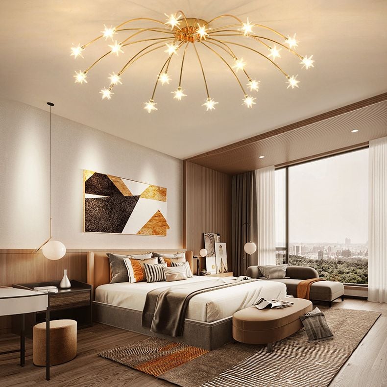 Gold-tone starburst ceiling fixture over bedroom with bed, desk and window seating, with separate globe pendants nearby