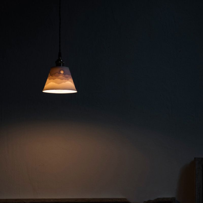Lit Lottie relief cone against a dark wall, casting light below the open rim