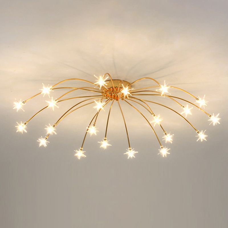 Gold-tone wide starburst ceiling lamp with lit glass stars on inner and outer curved arms against pale ceiling