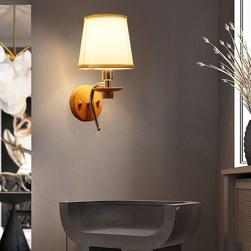 Eryn fabric-shade wall light with round wood plate and curved stem above a dark basin