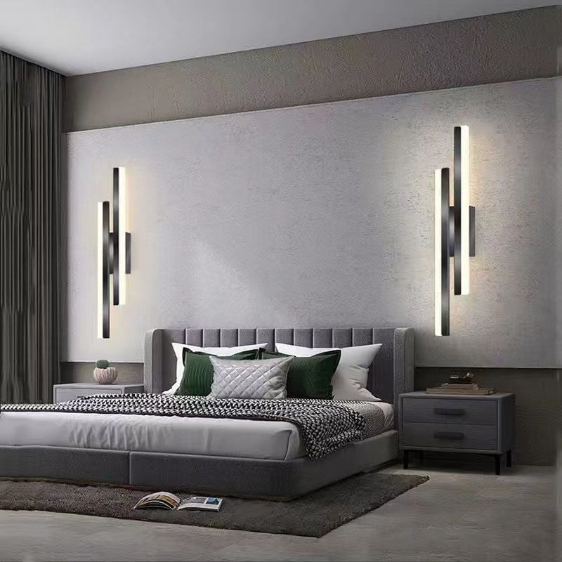 Two mirrored black offset-bar wall lights above a grey bed with upholstered headboard and nightstands