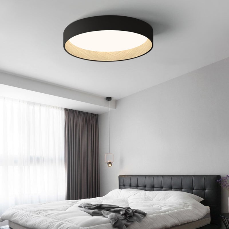 Black Quinn ceiling light above tufted bed and separate bedside pendant, with light wood-tone inner rim and glowing panel