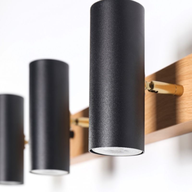 Angled close-up of three black cylindrical spots with gold-tone connectors on a wooden bar