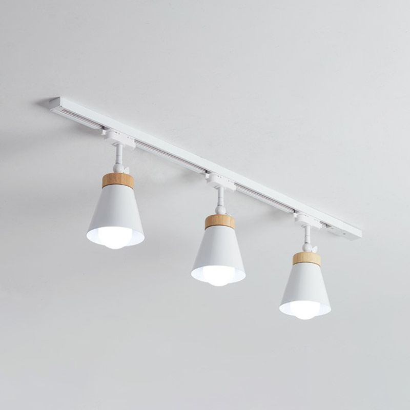 White Haney ceiling rail with three cone shades, short jointed stems, light wood-tone collars and visible bulbs
