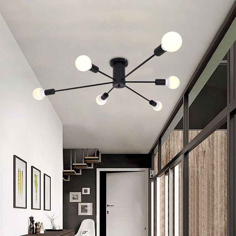 Black six-light radial-arm ceiling fixture above a dining area beside framed pictures and a glass partition