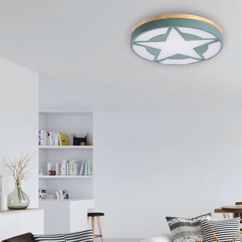 Green star-pattern ceiling light above a pale sofa, patterned cushions and white recessed bookcase