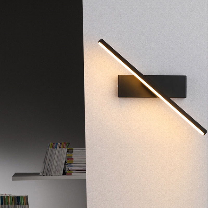 Diagonal black LED wall light beside a bookshelf