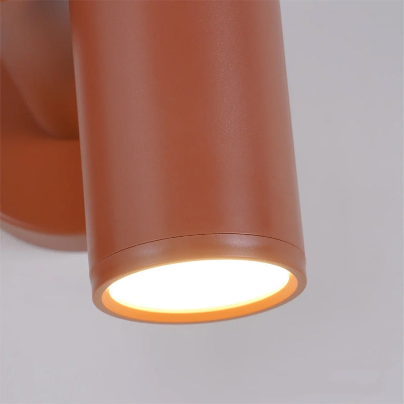 Close-up of one red cylindrical end, bright circular diffuser inside colored rim, fine seam and partial backplate behind