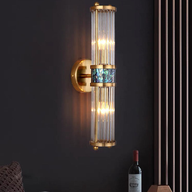 Clear-rod wall light on a dark wall beside a slatted panel, seat and wine bottle