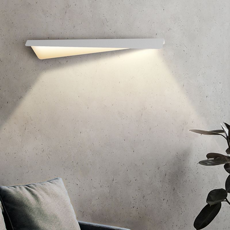 Leigh white linear wall light on a textured wall above a gray cushion beside a plant