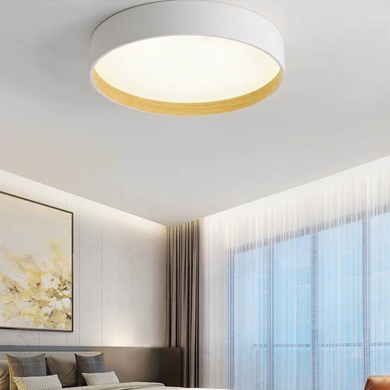 White Quinn ceiling light above bedroom with dark headboard, framed artwork and curtains, showing wood-tone inner rim