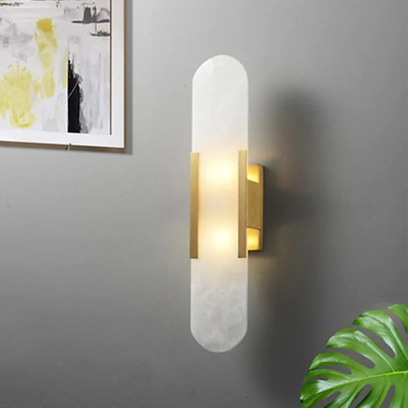 Gold-bracket Chan wall sconce glowing beside framed artwork