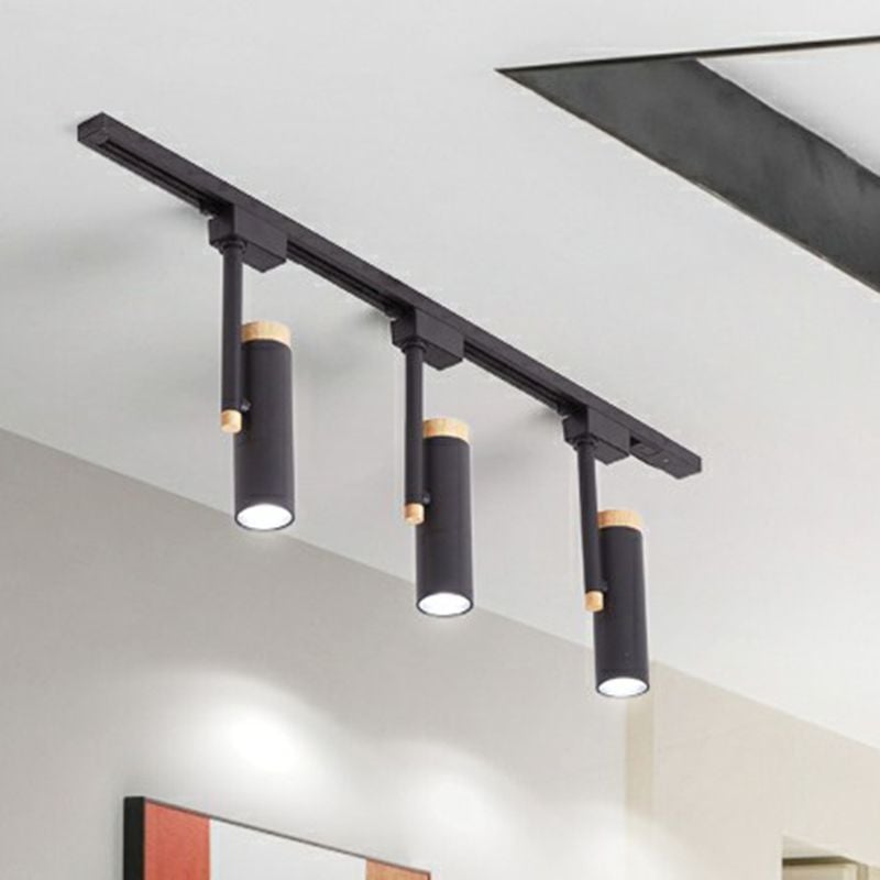 Black three-head ceiling spotlight rail casting light above framed wall art