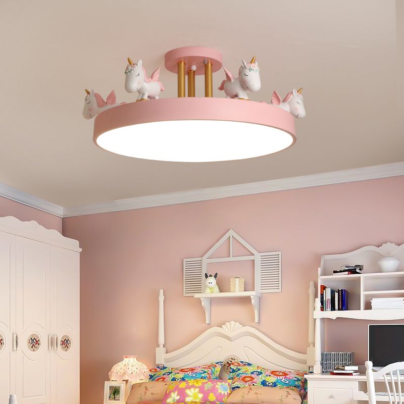 Pink unicorn ceiling light with gold-tone posts above patterned bedding, white wardrobe and desk