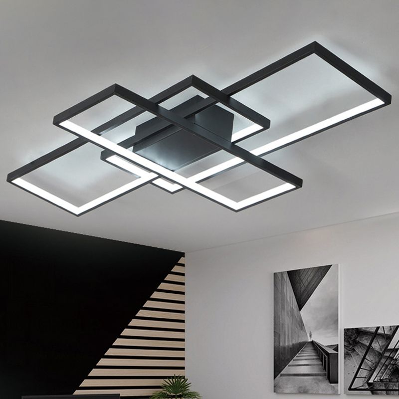 Black illuminated ceiling light with crossing rectangular frames beside a staircase and monochrome framed artwork