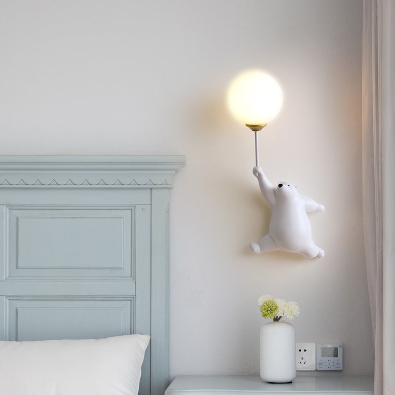 White bear wall light beside a pale green headboard
