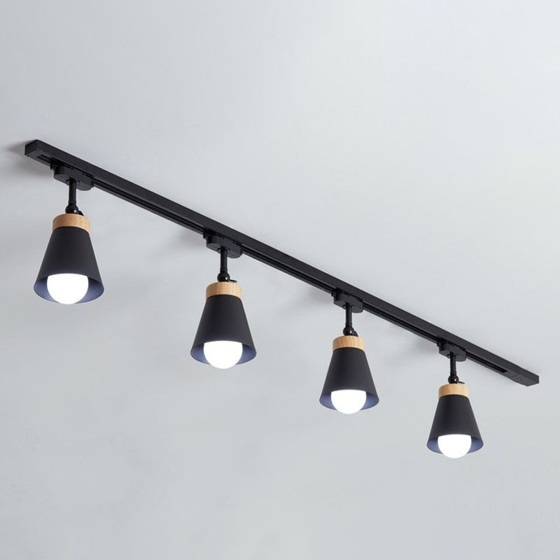 Black Haney ceiling rail with four cone shades and light wood-tone collars, heads pointing down with visible bulbs
