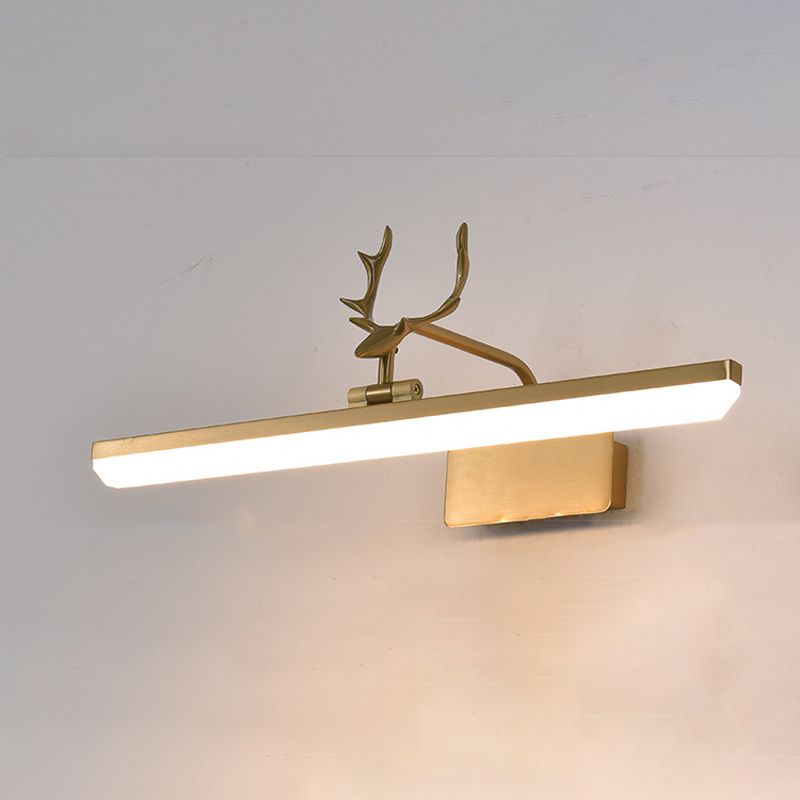 Gold-tone antler wall light glowing against a gray wall, showing the straight bar, central joint and wall plate