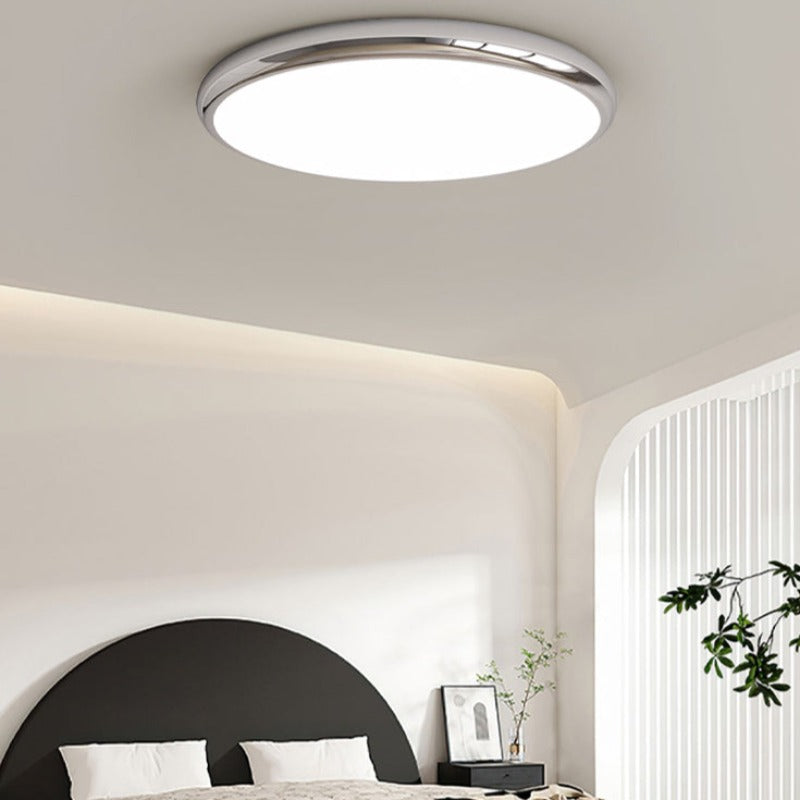 Silver-coloured Ozawa ceiling light above a bed with a black curved headboard.