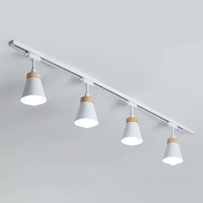 White Haney ceiling rail with four cone shades and light wood-tone collars, heads pointing down with visible bulbs