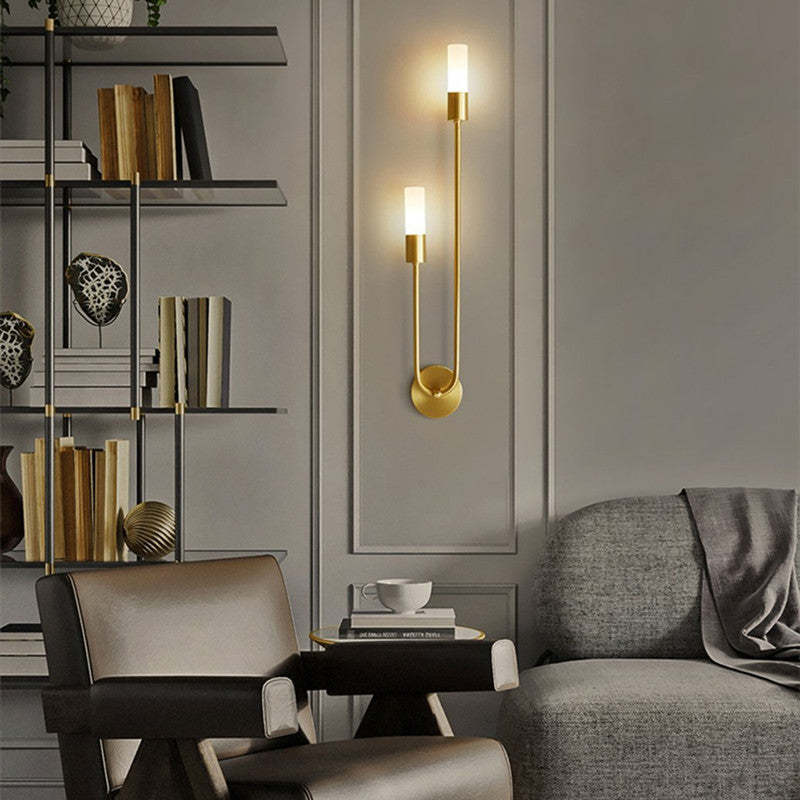 Upward-oriented gold Meza sconce with white light tips above a sofa.