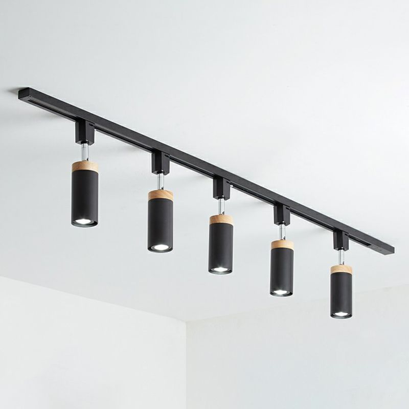 Black five-head ceiling rail fixture with cylindrical spotlights pointing down and tan top collars