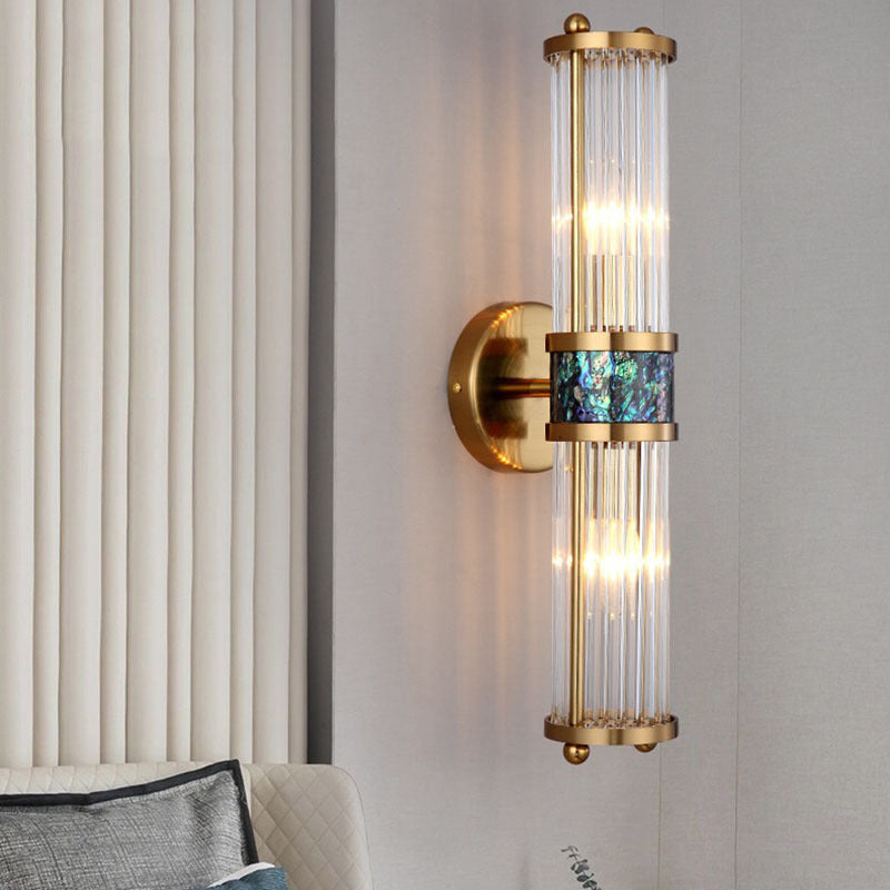 Gold-tone rod wall light with blue-green center near pale curtains and upholstered furniture