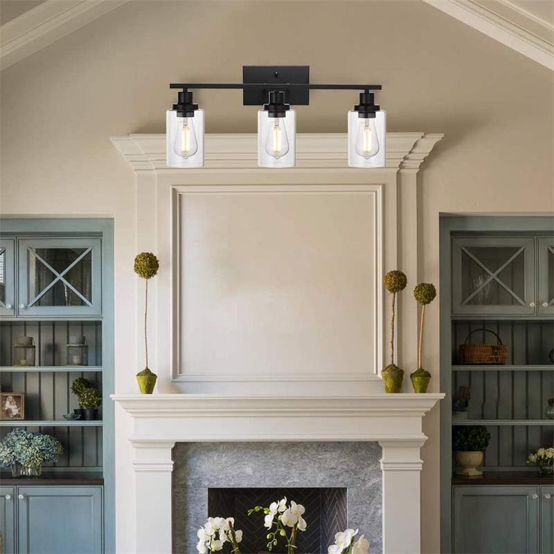 Black Alessio three-light bar with downward glass cylinders above a mantel and vases