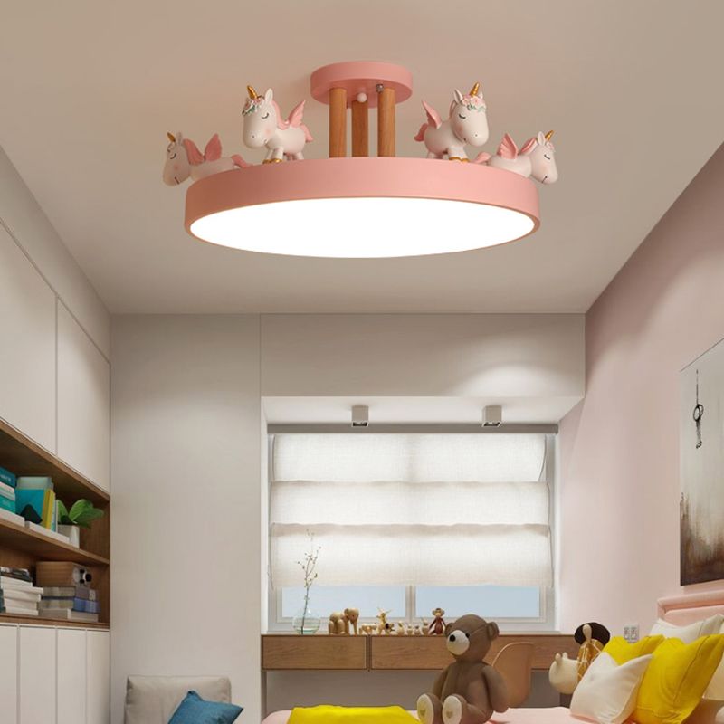 Pink unicorn ceiling light with wood-tone posts above a bear toy, yellow cushions and bedroom storage