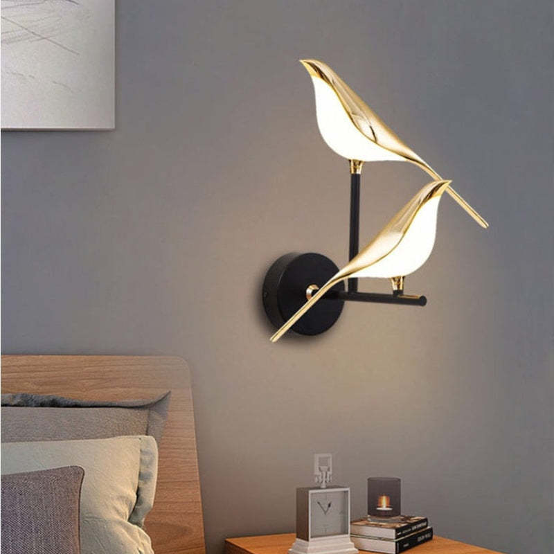 Gold bird wall light above a bedside table