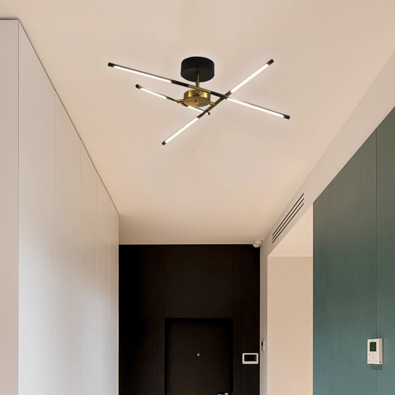 Black and gold crossed-bar ceiling light with six luminous ends above a doorway