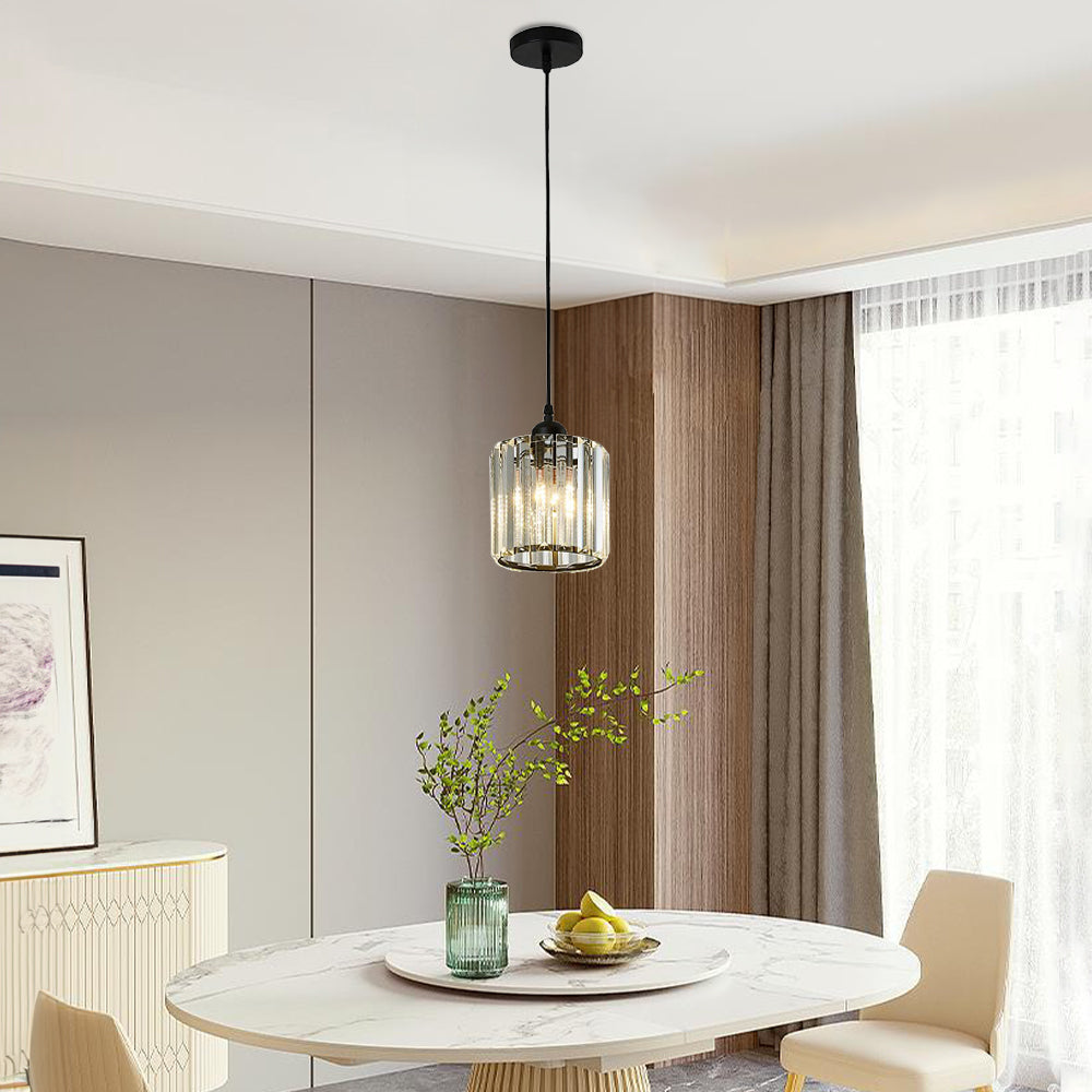 Single black Herbert cylindrical glass pendant above a round table with a vase and pears near a window